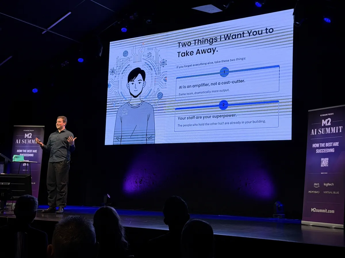Blake Harkness presenting on stage at the M2 AI Summit in Christchurch, with a slide reading Two Things I Want You to Take Away